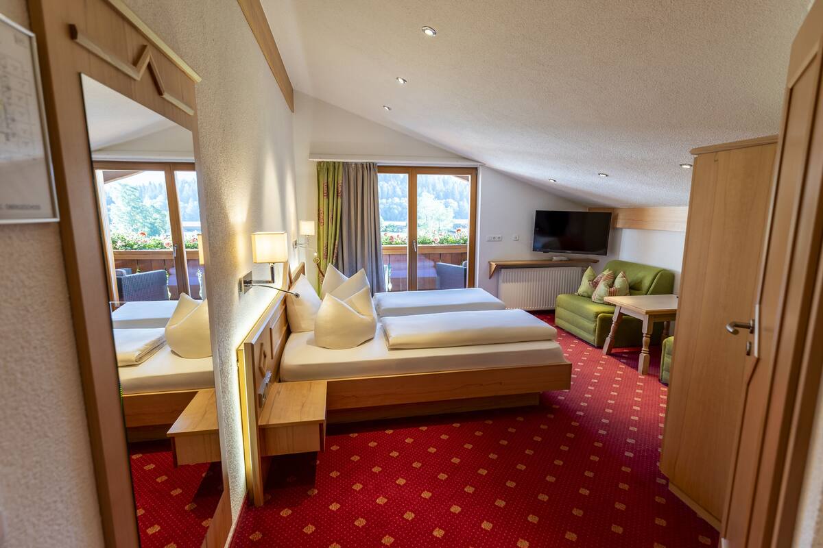 A hotel room with a bed, a desk, a TV, and a view of the outdoors.