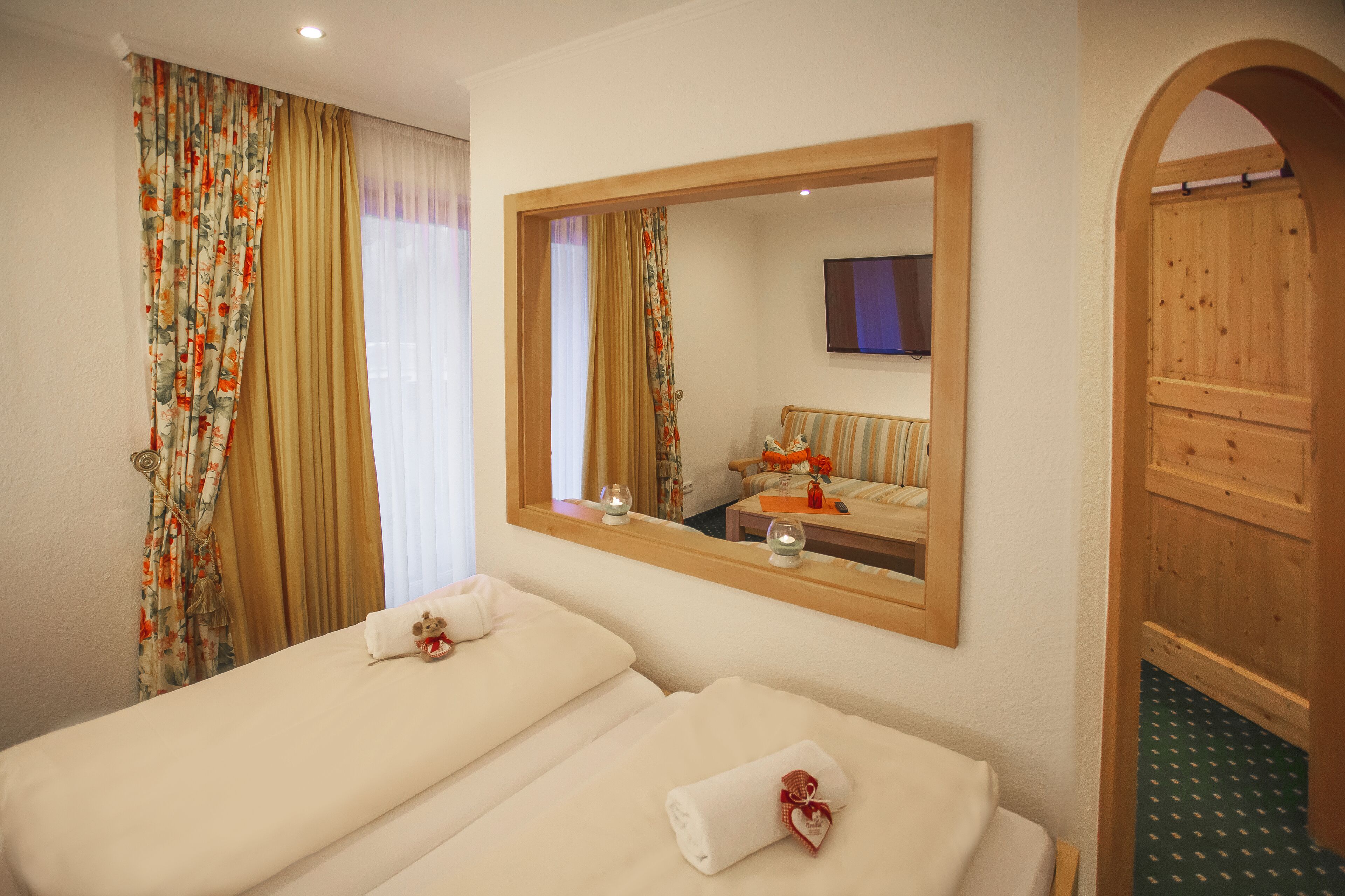 A hotel room with two beds, a large mirror, and a wooden door.