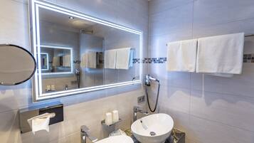 A modern bathroom with two sinks, a large mirror with LED lighting, and neatly arranged towels.