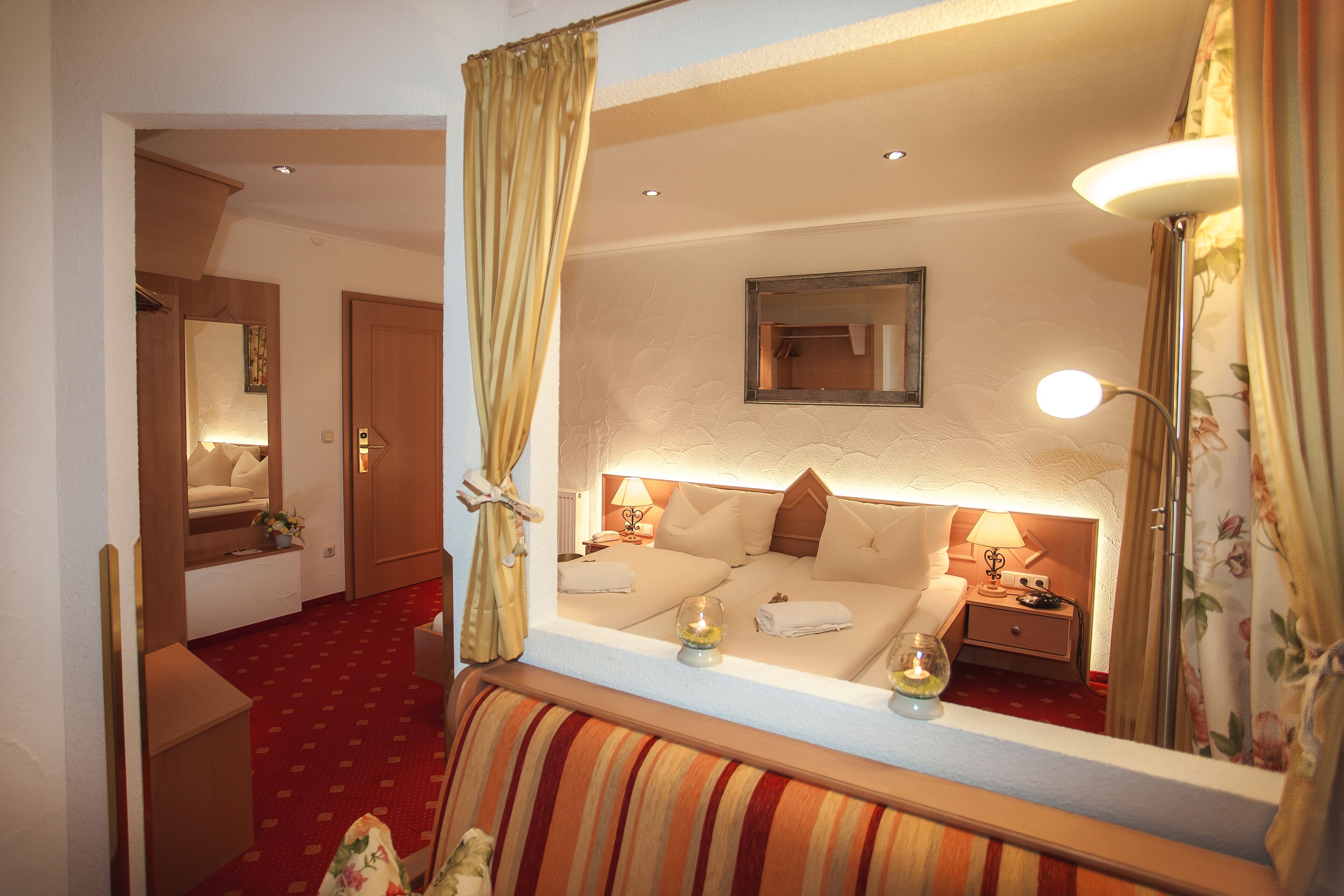 Une chambre d’hôtel avec un lit, des lampes de chevet, un miroir et une moquette rouge.