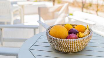 Uma tigela de vime cheia de frutas sobre uma mesa branca ao ar livre.