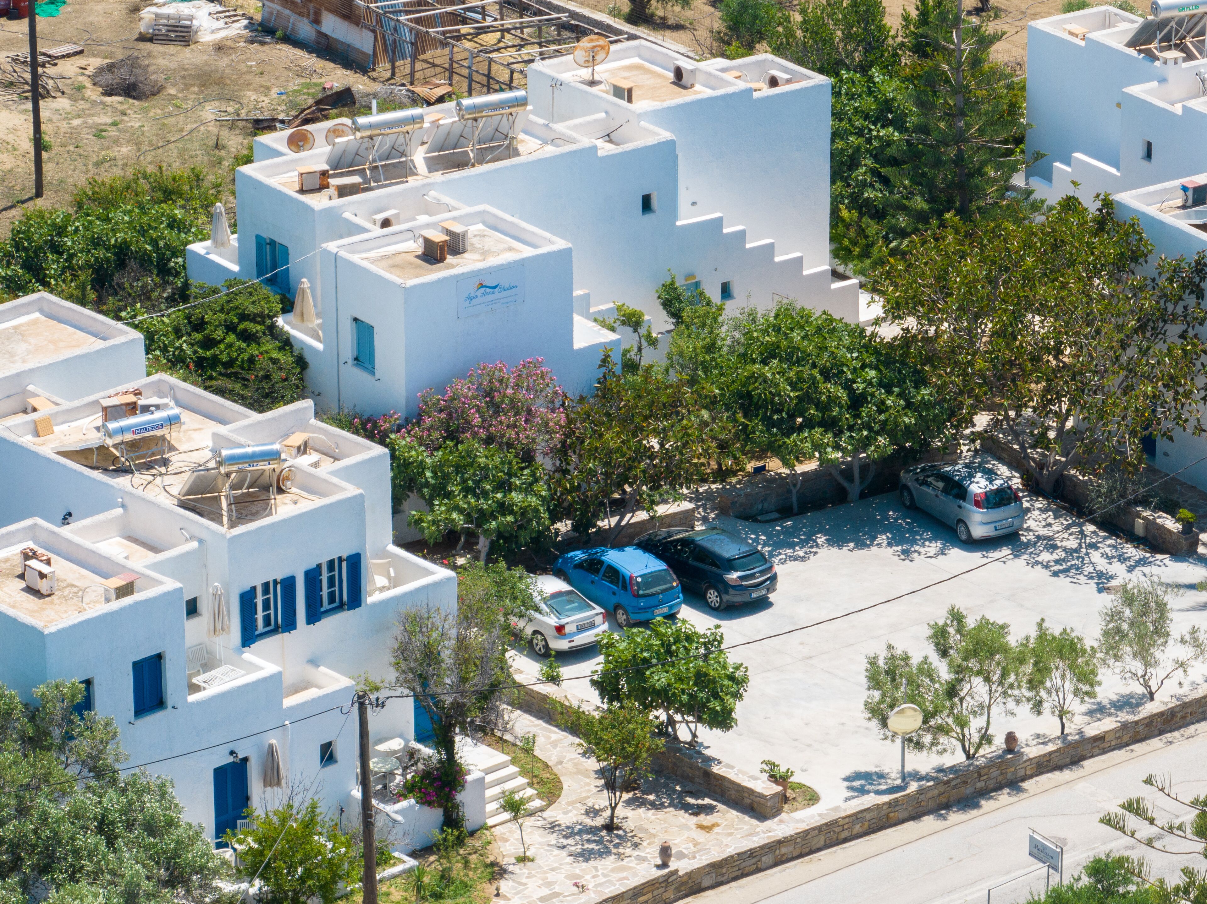 Área residencial com edifícios brancos, painéis solares e carros estacionados.
