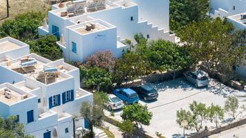 Área residencial com edifícios brancos, painéis solares e carros estacionados.