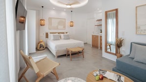 Et moderne hotelværelse med seng, sofa, spisebord og fjernsyn ophængt på væggen.