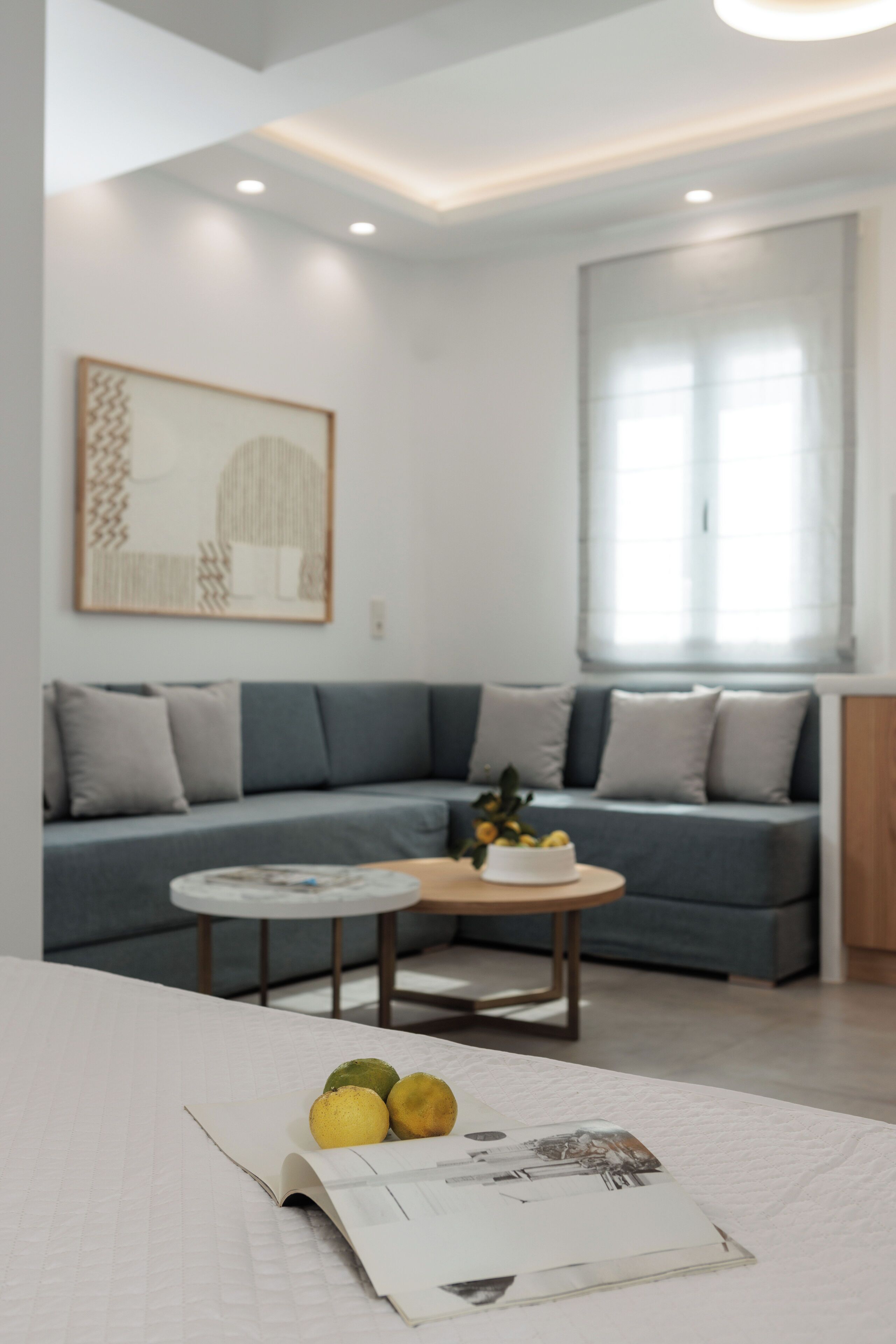 A modern living room with a grey sofa, a round coffee table, and a book on a white surface.