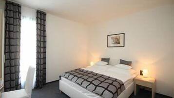 Une chambre d’hôtel avec un lit, une chaise, une table de chevet et un tableau accroché au mur.