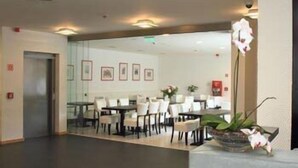 A hotel lobby with a reception desk, seating area, and framed artwork on the walls. - Hotel Arkadia (Pecs)