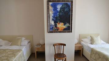 Ein Hotelzimmer mit zwei Betten, einem Holzstuhl, einem Nachttisch und einem Gemälde an der Wand.