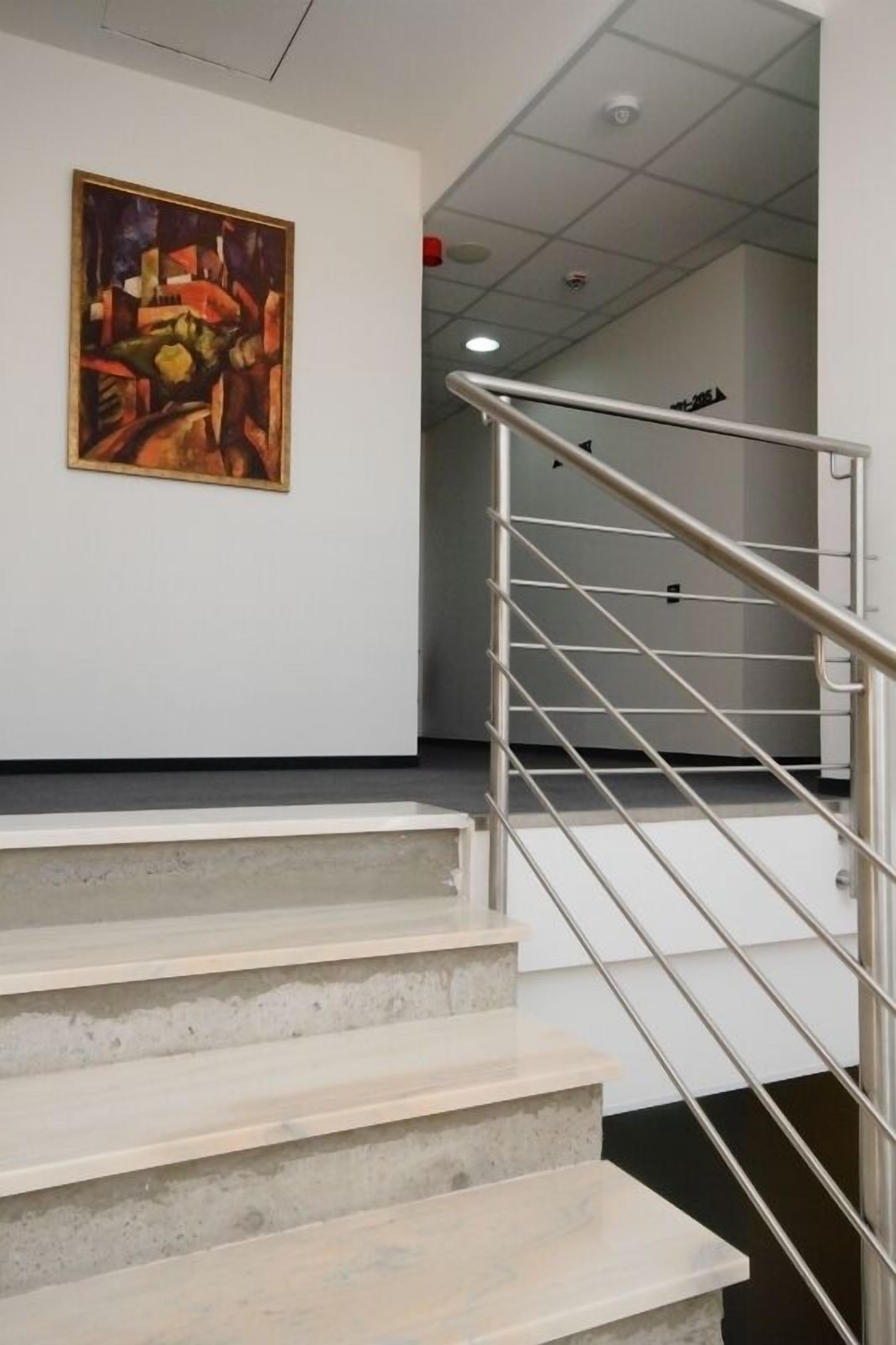 A staircase with a metal handrail leading to a room with a painting on the wall.