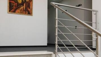 A staircase with a metal handrail leading to a room with a painting on the wall.
