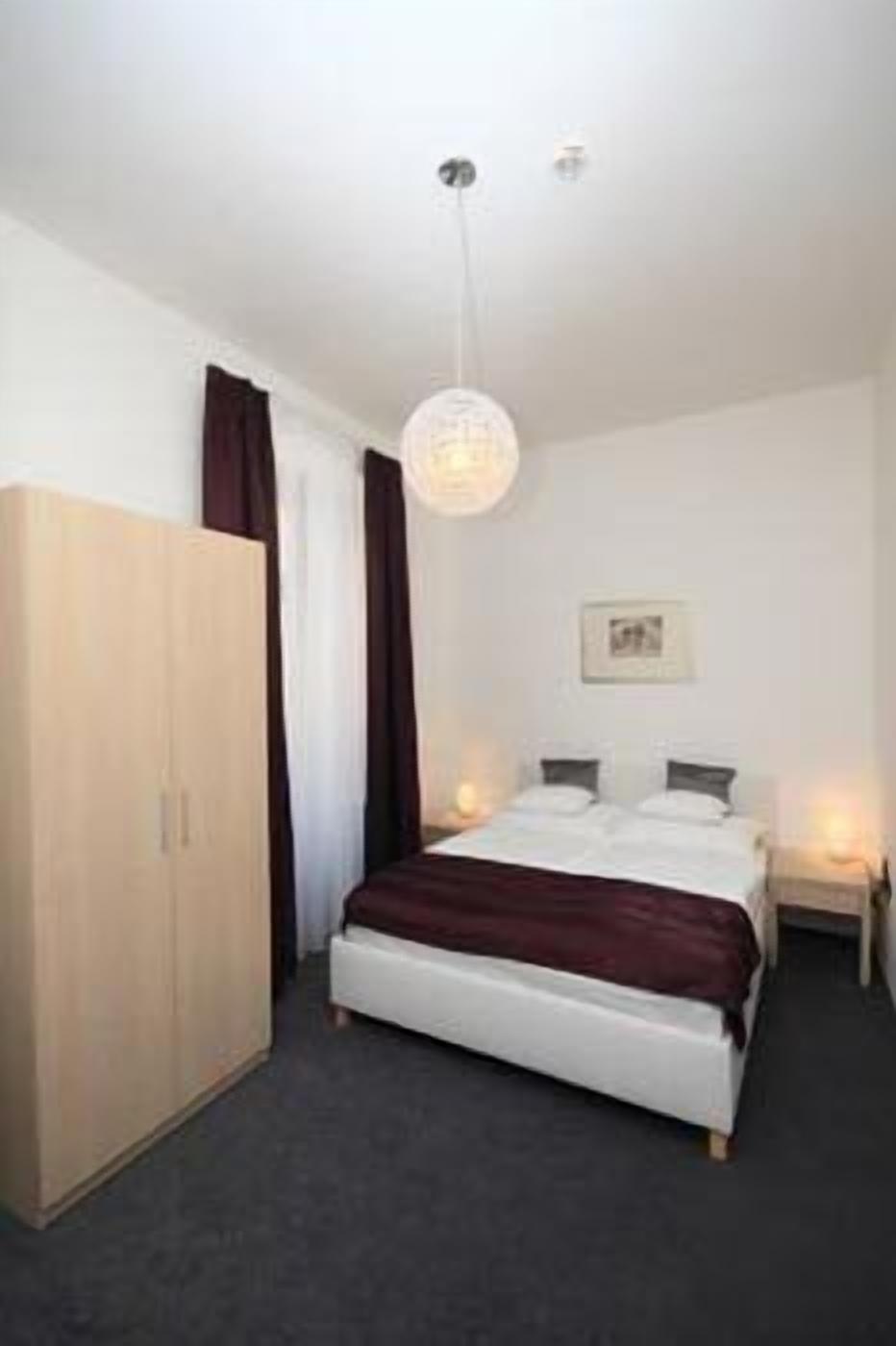 A bedroom with a bed, a wardrobe, a hanging light fixture, and a framed picture on the wall.