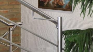 Ein Gemälde einer muskulösen Figur mit Bogen und Pfeil an einer weißen, strukturierten Wand.