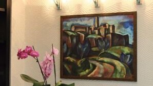 A painting on a wall with a textured surface and a vase with pink flowers in the foreground. - Hotel Arkadia (Pecs)
