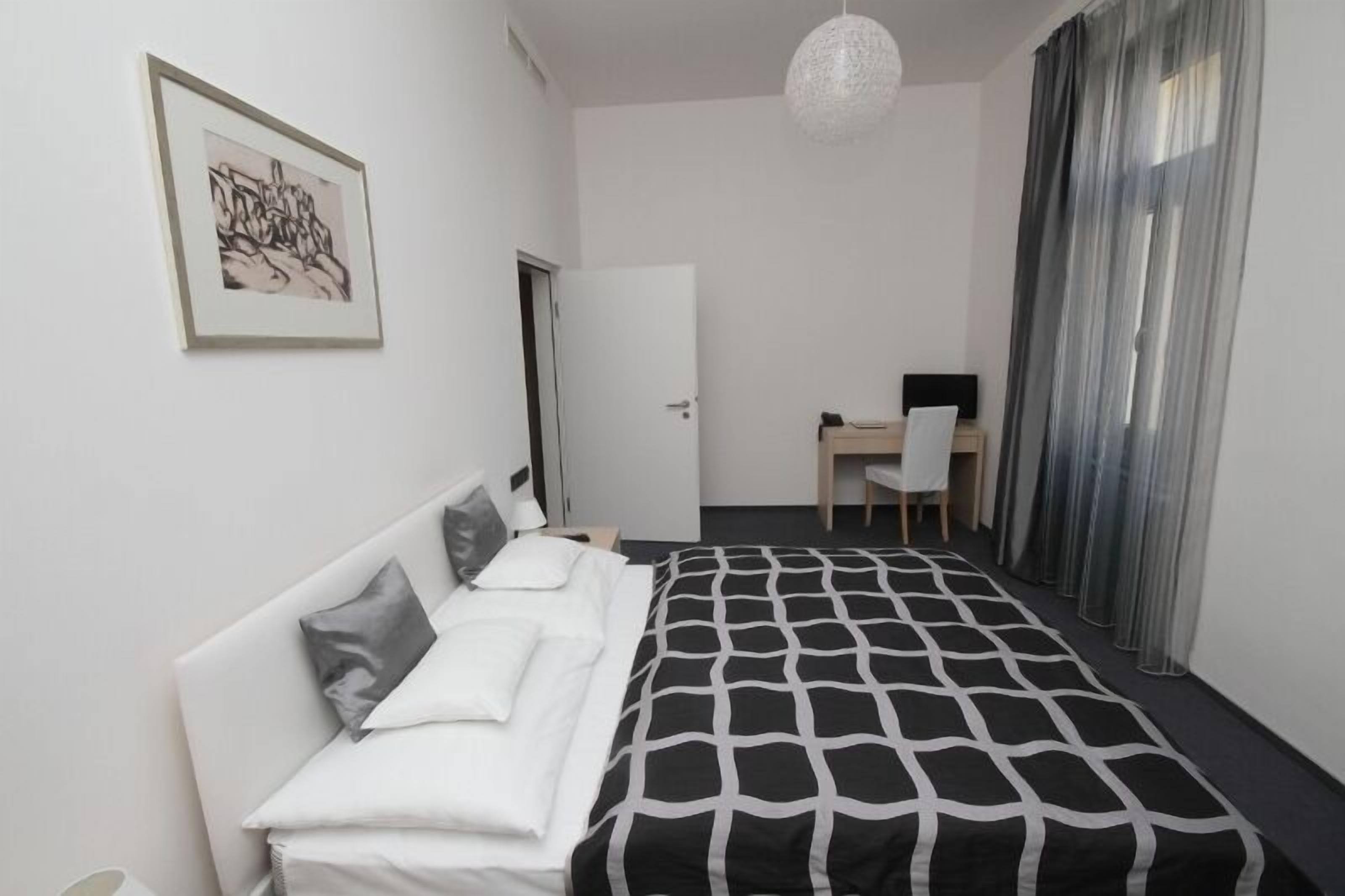 A bedroom with a bed, a desk, and a chair.