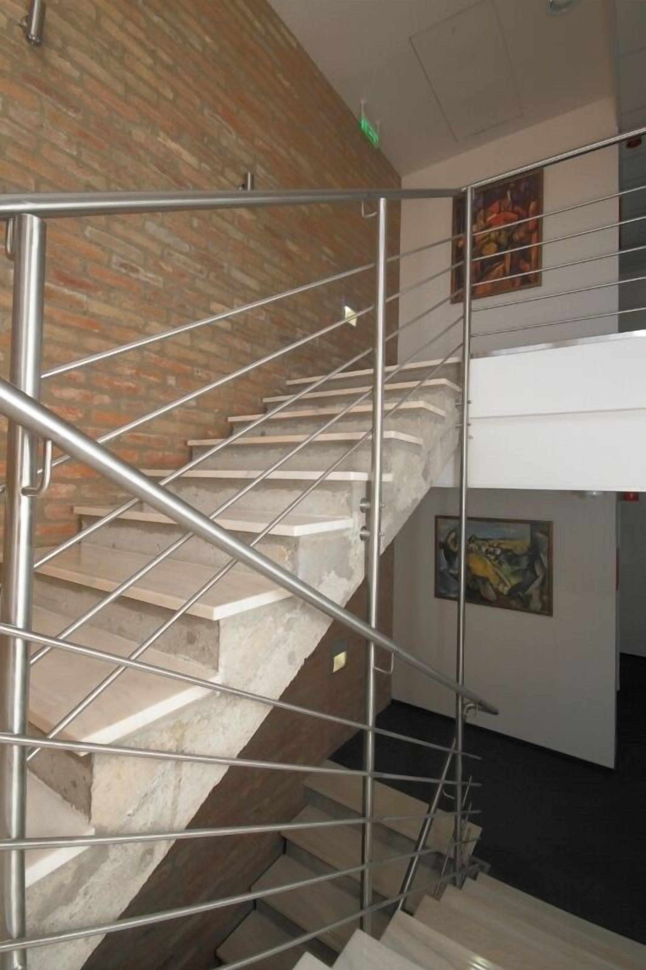 A staircase with metal railings, a brick wall, and artwork on the walls.