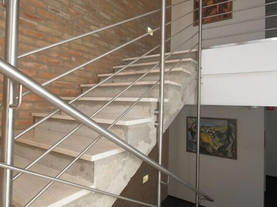 A staircase with metal railings, a brick wall, and artwork on the walls.