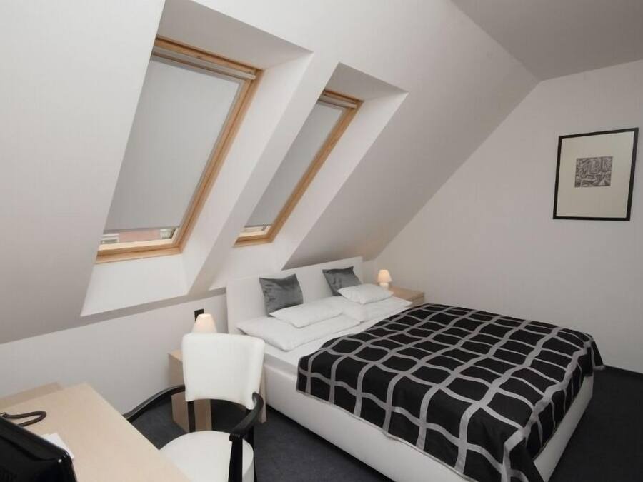 Un dormitorio con cama, escritorio y dos tragaluces.
