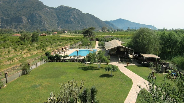 A resort with a swimming pool, outdoor seating, and a mountain backdrop.