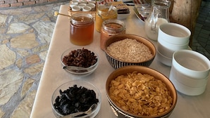 A buffet table with various food items and condiments, a bar area with bottles and glasses, and a stone wall backdrop.