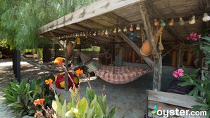 A rustic outdoor seating area with a hammock, wooden benches, and hanging lanterns.