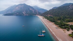 Eine Luftaufnahme einer Küstenlandschaft mit Strand, Booten und Bergen.