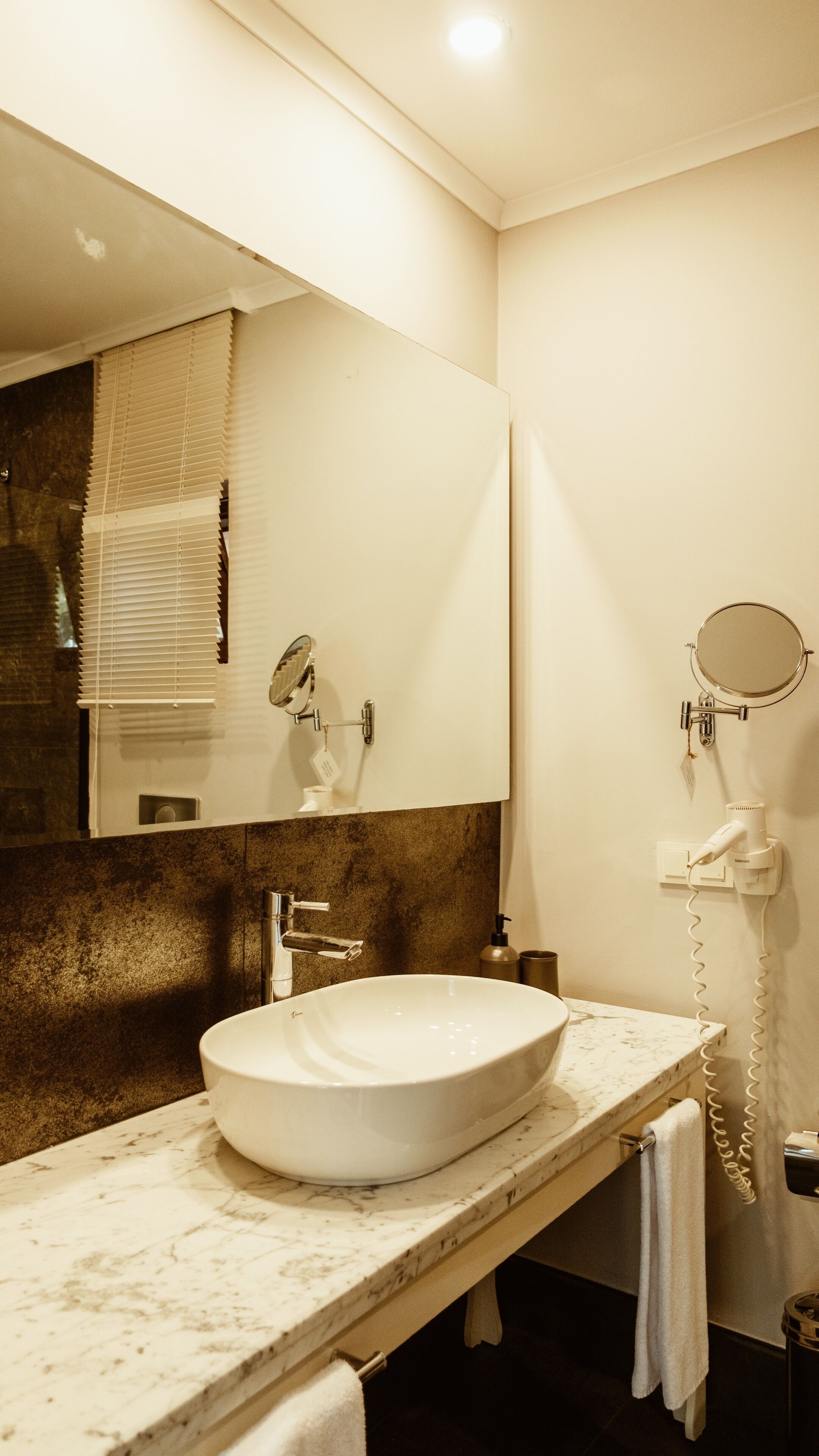 A bathroom with a large mirror, a sink, and a hairdryer.