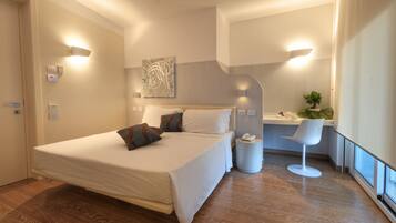 A modern hotel room with a large bed, bedside lamps, a small desk, and a chair.