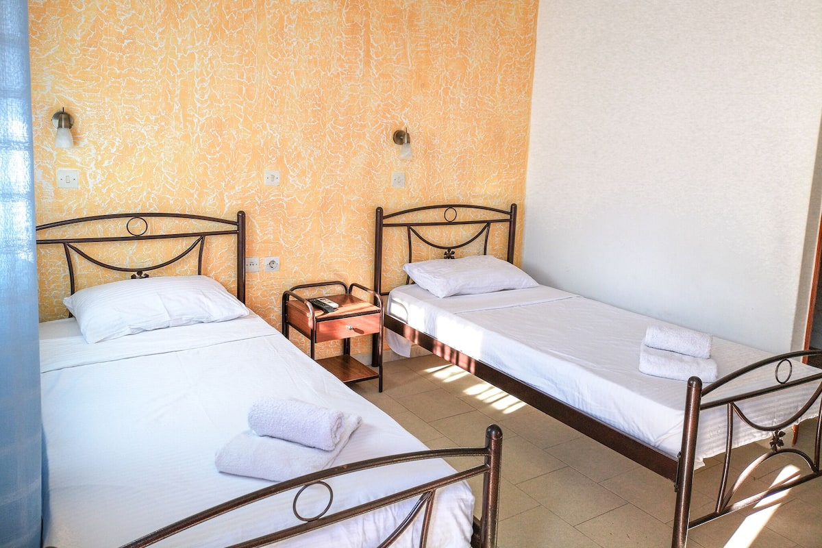Une chambre d’hôtel avec deux lits simples, une table de chevet et un mur orné d’un motif texturé.