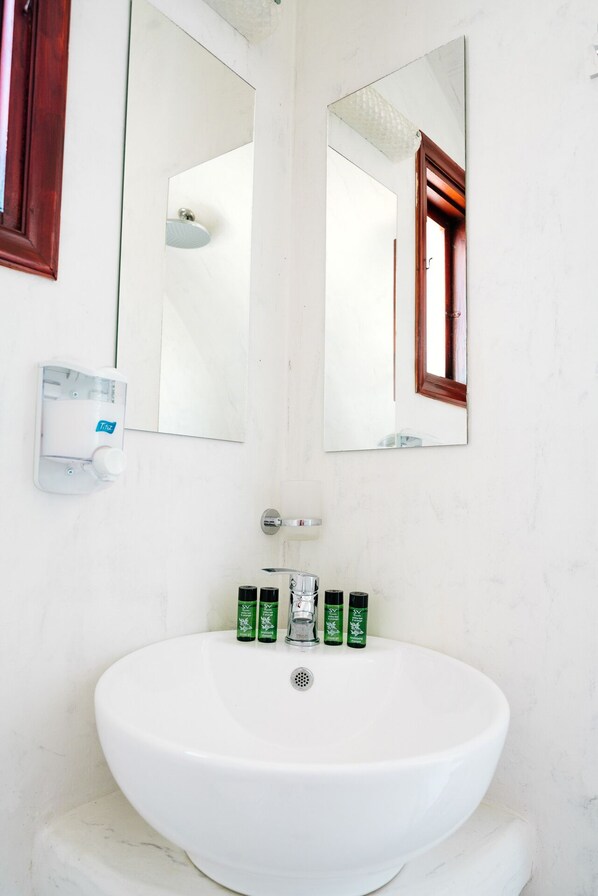 Une salle de bain blanche avec un grand miroir, un lavabo et un sèche-mains.