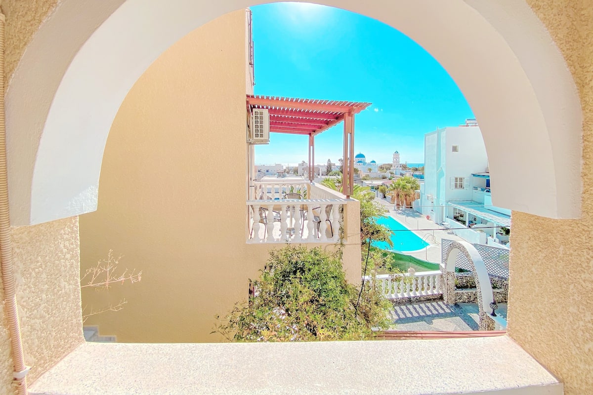 Un balcon donnant sur une piscine, une pergola et une clôture blanche.