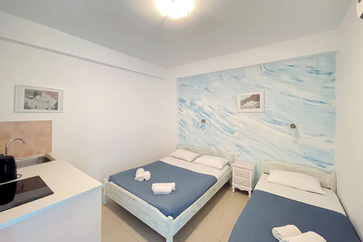 Une chambre avec deux lits, une table de chevet et une lampe fixée au mur.