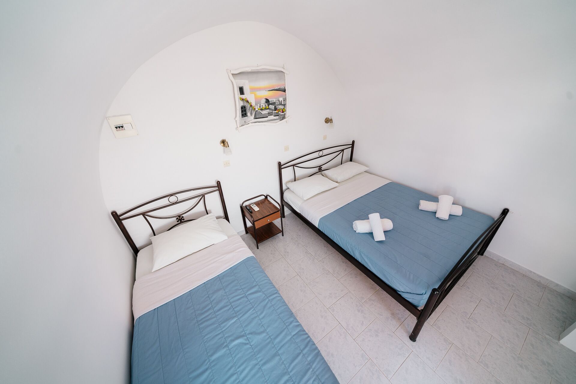 Une chambre avec deux lits, une petite table et un tableau accroché au mur.