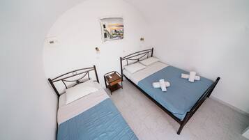 Une chambre avec deux lits, une petite table et un tableau accroché au mur.