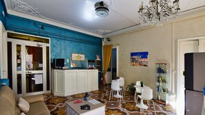 A hotel lobby with a beige sofa, a white table, a glass display case, and a chandelier. - Hotel Suisse Genova (Genoa)