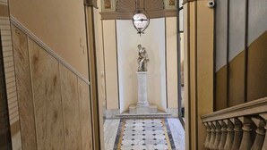 A grand hallway with a marble floor, a statue at the end, and a decorative ceiling. - Hotel Suisse Genova (Genoa)
