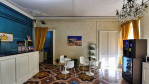 A room with a patterned floor, a refrigerator, a dining area with chairs, and a small table with a plant. - Hotel Suisse Genova (Genoa)