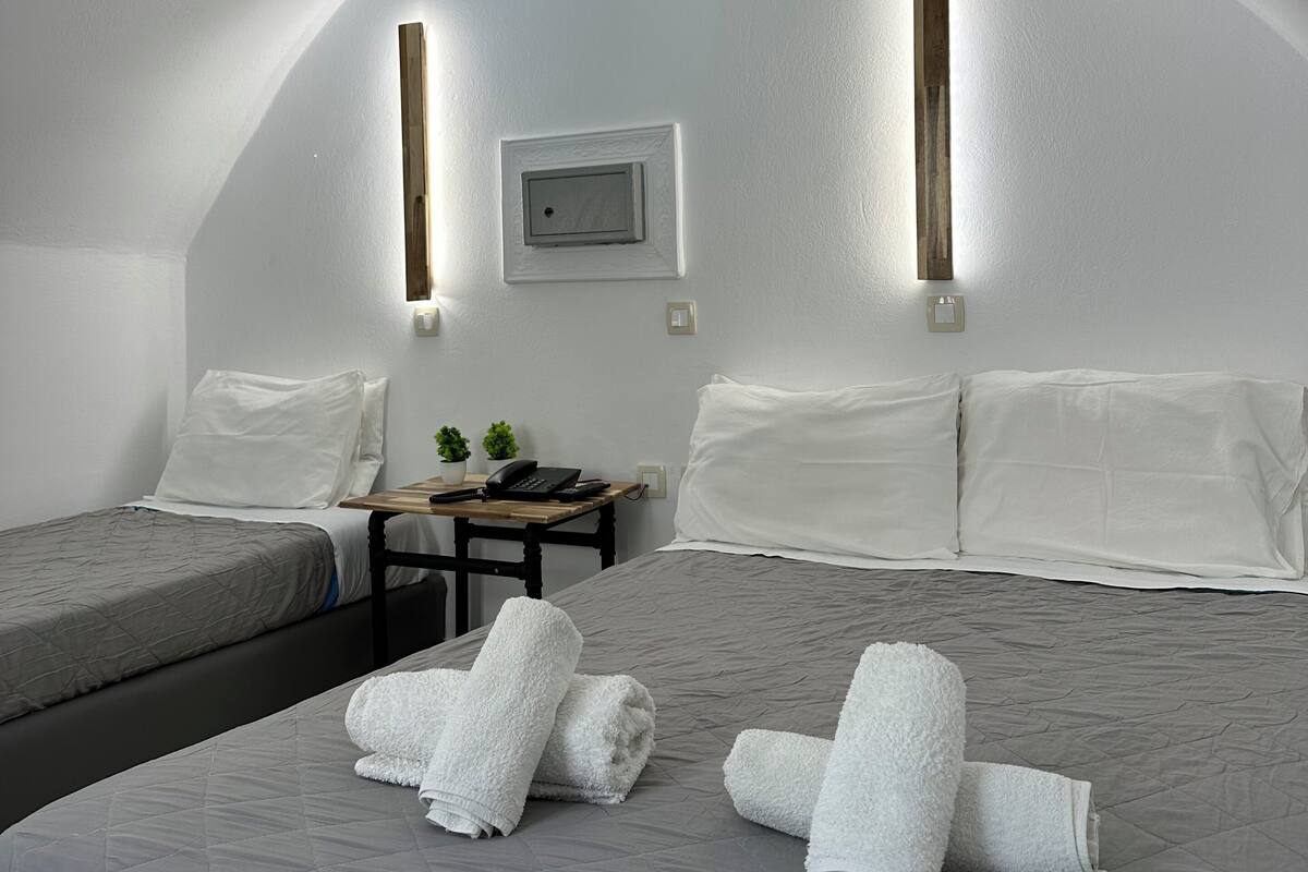 A compact room with a bed, a small desk, and a wall-mounted TV.