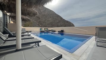 Una piscina al aire libre, sombrillas, tumbonas