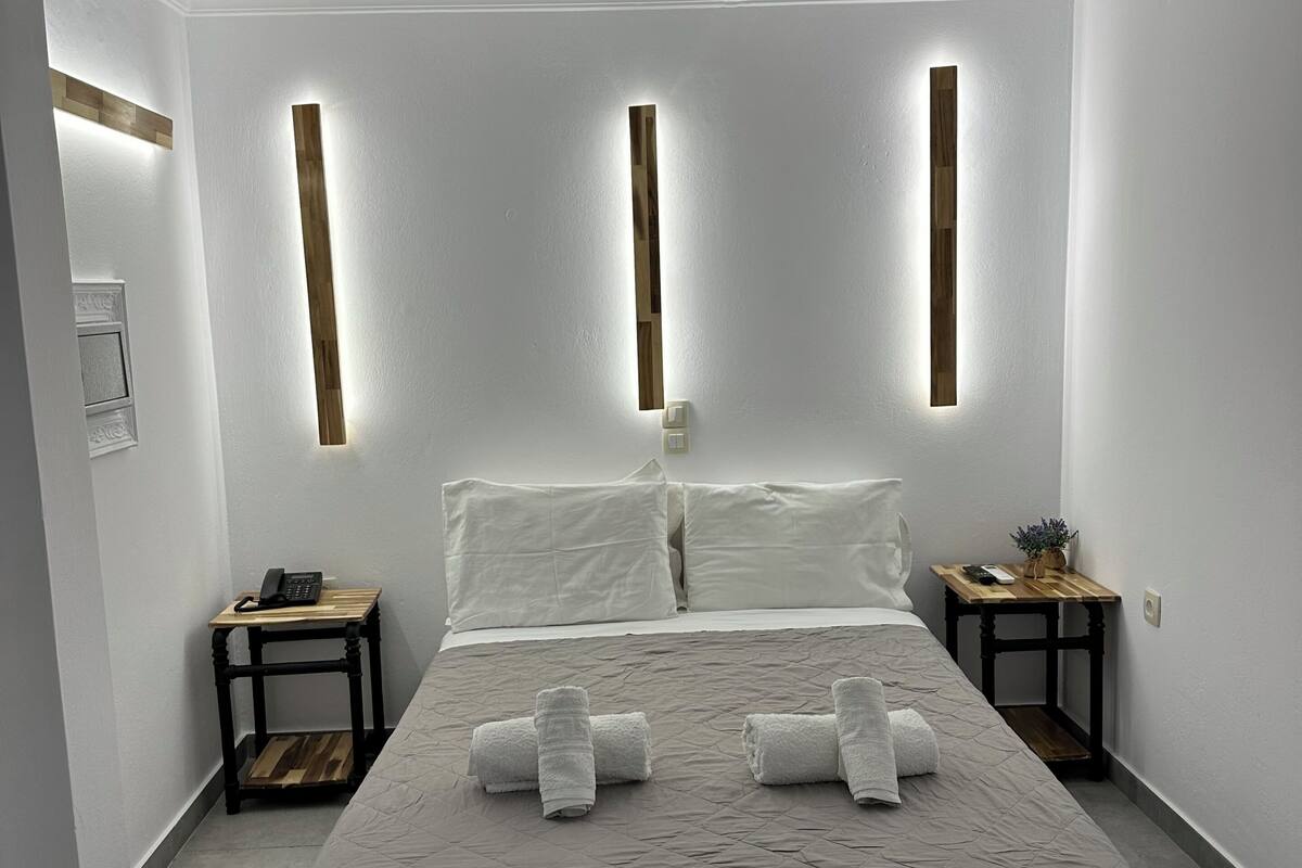A modern bedroom with a large bed, bedside tables, and wall-mounted lighting.