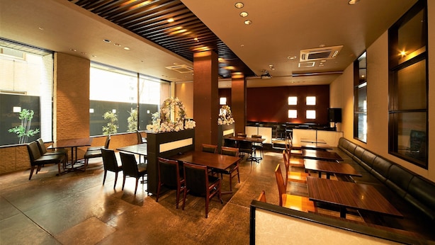 A modern restaurant with wooden tables and chairs, a bar area, and large windows providing natural light. - Toyo Hotel (Fukuoka)
