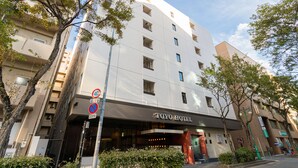 A modern hotel with a prominent entrance, multiple floors, and a clear sky. - Toyo Hotel (Fukuoka)