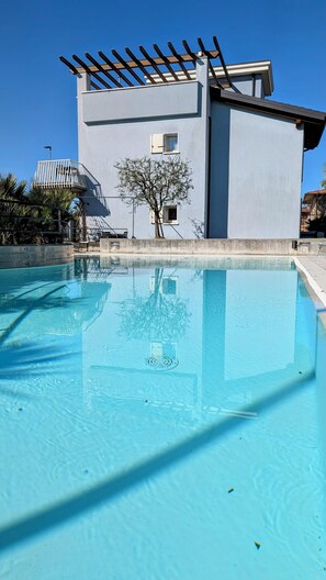 Een buitenzwembad, parasols bij het zwembad en ligstoelen