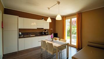 A modern kitchen with white cabinets, a dining table with chairs, and a sofa.