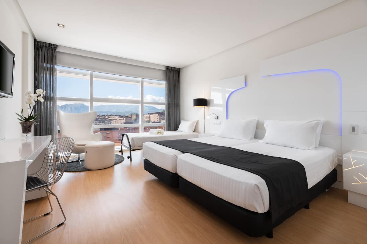 A modern hotel room with a large bed, a desk, and a chair.