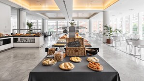 Àrea interior àmplia amb una taula de buffet que mostra diversos plats, un quadre negre i mobles moderns.