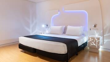 Ein modernes Schlafzimmer mit einem großen Bett, einem Kopfteil mit integrierter Beleuchtung, einem Nachttisch mit Lampe und Holzboden.