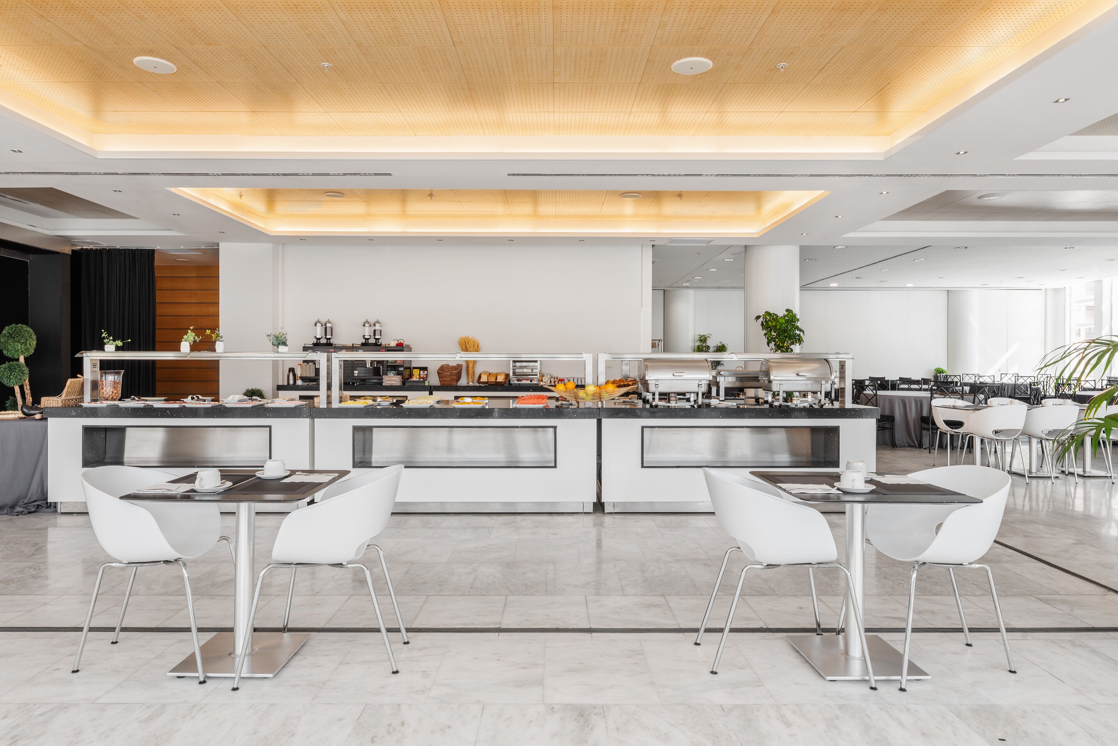 A modern kitchen with a central island, white chairs, and a dining area with a long table.