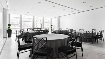 Un salón de conferencias moderno con una mesa redonda rodeada de sillas, ventanas amplias y vistas panorámicas de la ciudad.