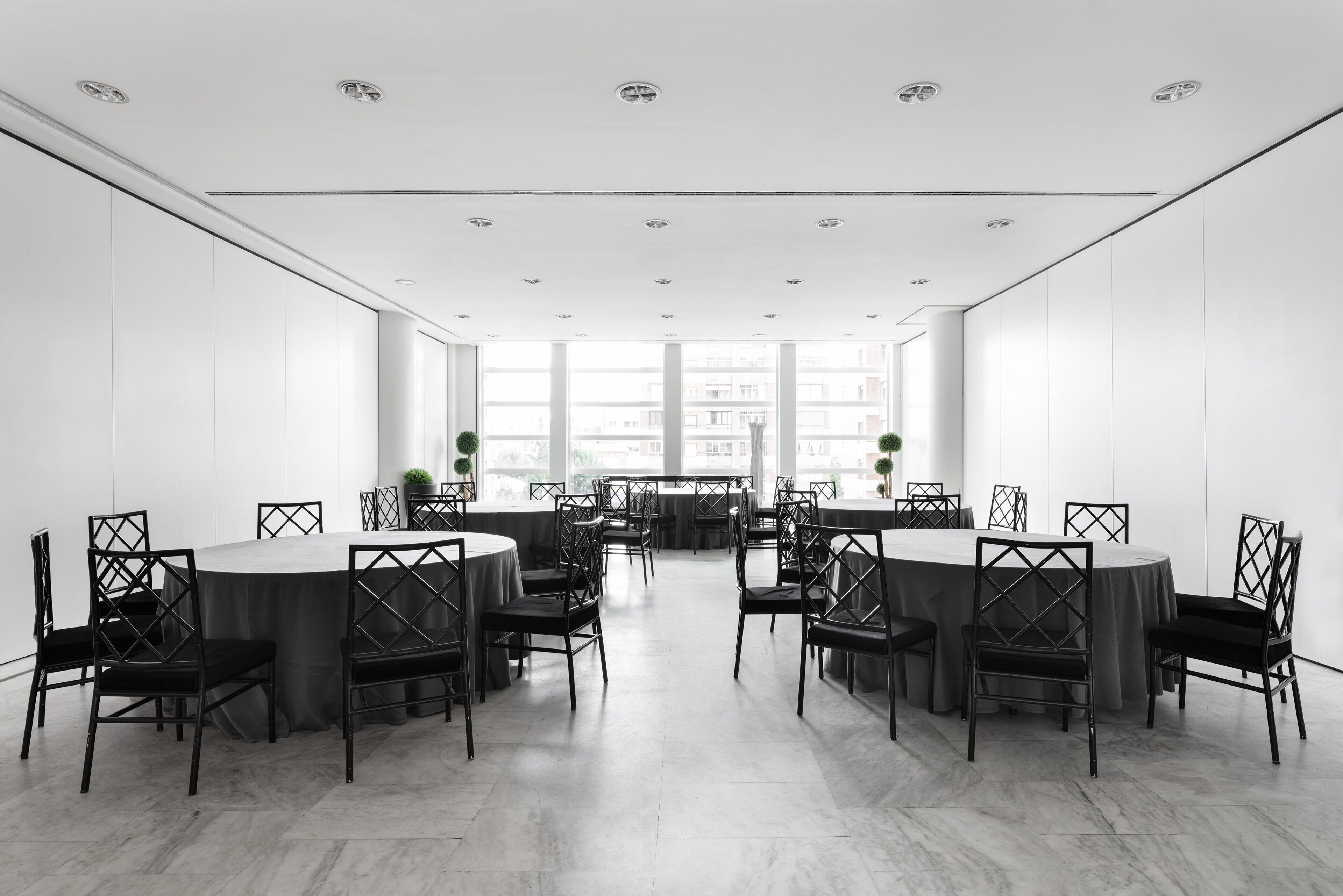 A conference room with round tables and chairs, large windows, and a white interior.