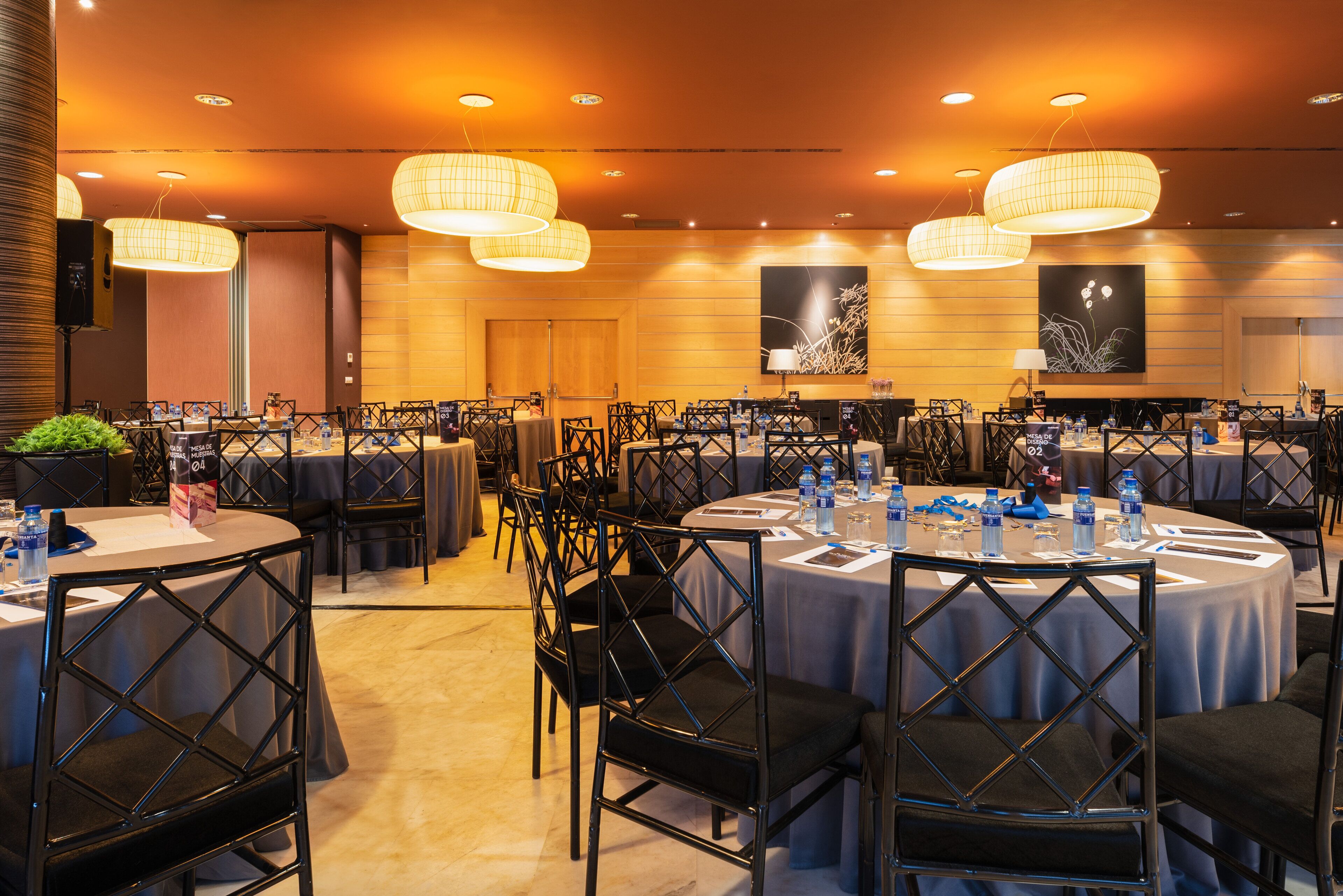 A conference room with round tables, black chairs, and overhead lighting.